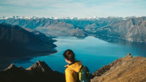 woman in yellow hoodie overlooking the beautiful view of lake scenery